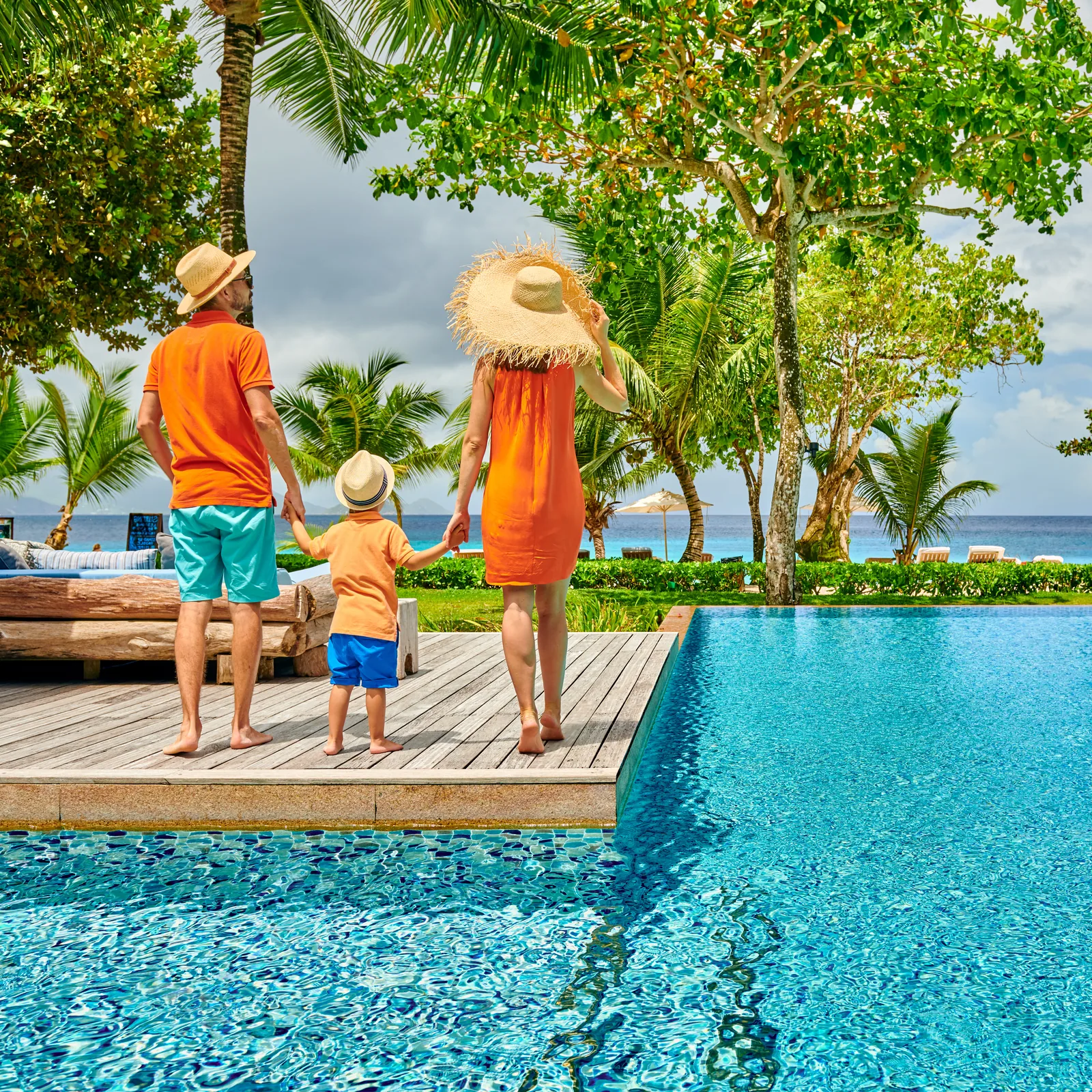 Family relaxing together beside a tropical pool